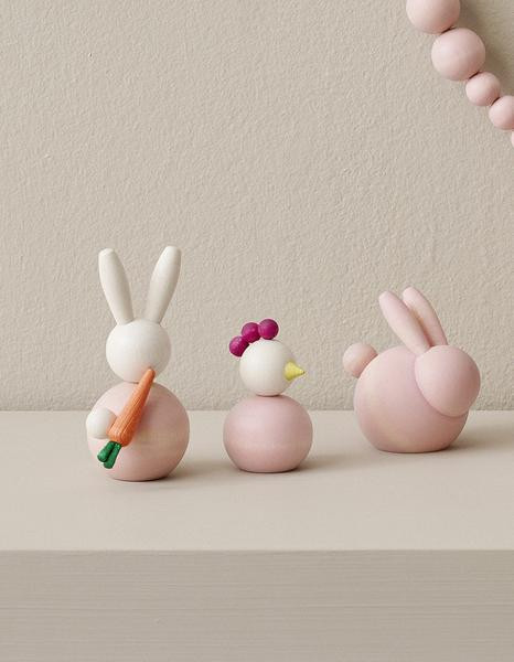 Pink wooden bunny and chicken figures on a light surface.