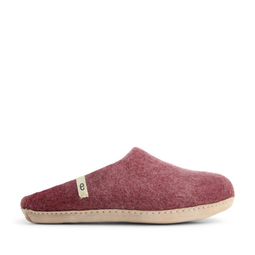 Side view of a bordeaux wool felt slipper with a light tan suede sole and small brand tag.