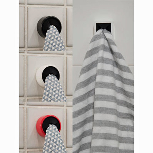 Black, white, and red dishcloth hangers on tiled wall, one with striped towel.