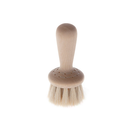 A wooden face brush with white horsehair bristles, angled slightly to the right on white.