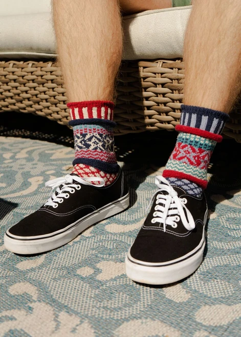 Black low-top sneakers and patterned crew socks featuring red, white, and blue stripes.