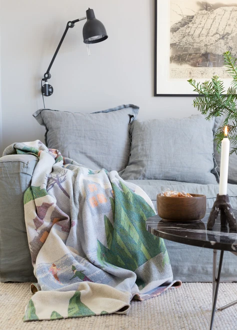 Grey linen sofa with the Vinterliv organic cotton throw blanket draped across it.
