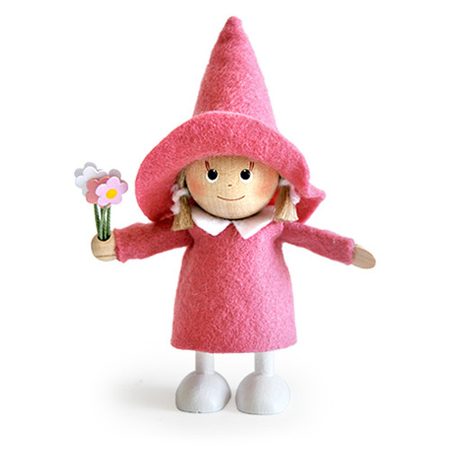 Handmade wooden girl figurine in a pink dress and witch hat holding paper flowers.