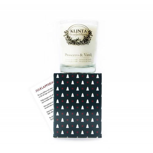 Klinta scented soy candle in a glass jar, resting on a black box with white Christmas tree patterns.