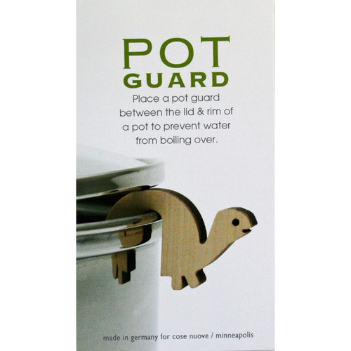 Packaging for a wooden turtle pot guard, shown propping open a stainless steel pot lid.