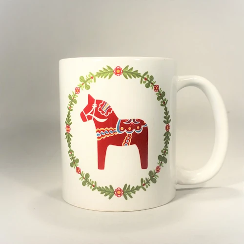 White ceramic mug featuring a red Dala horse within a green floral wreath.