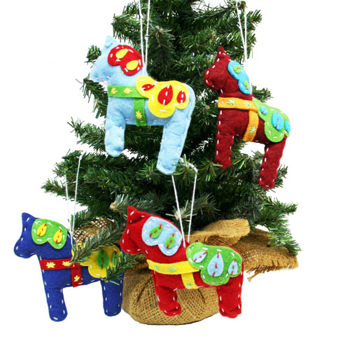 Four felt Dala horse ornaments in red, blue, and light blue hang on a Christmas tree.