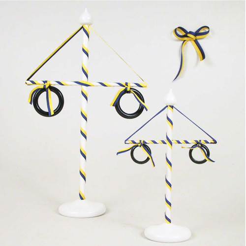 White wooden Midsummer pole with blue and yellow ribbons, black rings, and a bow.