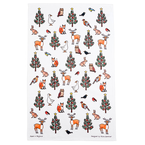 White cotton Christmas tea towel featuring a festive winter wildlife pattern of trees, deer, foxes, and birds.