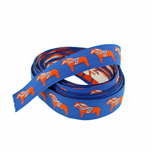 Blue ribbon with repeating orange Dala horse pattern, rolled up. Polyester jacquard material.