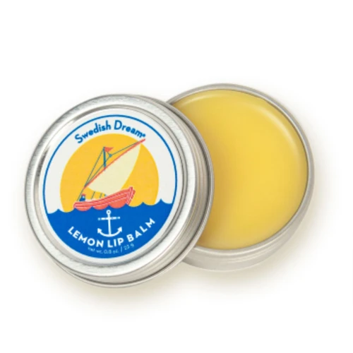 Swedish Dream Lemon Lip Balm tin, open, with yellow balm. Silver metal, nautical design, white background.