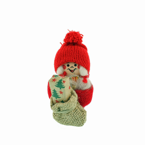 Wooden Tomte girl figurine in red knit hat holding a gift in a burlap sack.