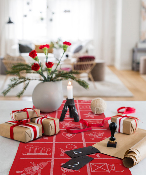 Red organic cotton-linen table runner featuring a white geometric grid and holiday motifs on a table.