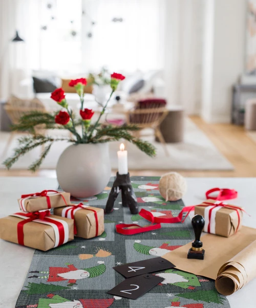 Gray Ekelund organic cotton table runner featuring a festive red and green Christmas elves pattern.