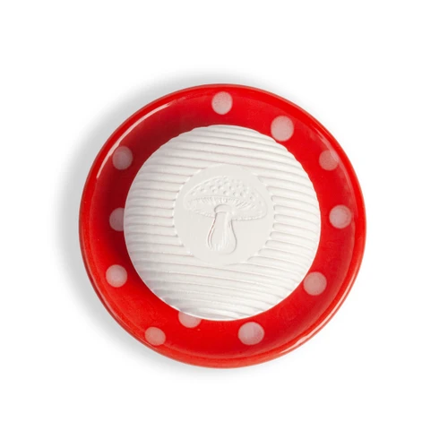 Top-down view of a round red ceramic soap dish with white polka dots holding a white grooved soap bar embossed with a