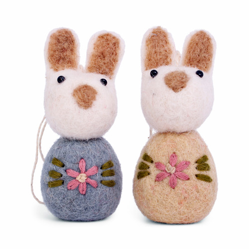 Two handmade felt bunny ornaments in blue and beige with embroidered pink flowers.