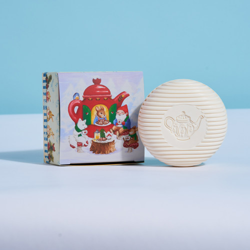 Off-white round soap with a teapot stamp, next to its illustrated box showing gnomes.