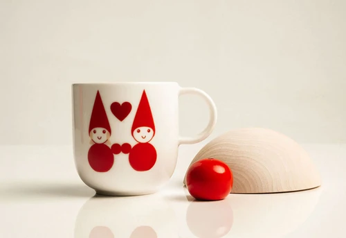White ceramic mug with red elf illustration and heart.
