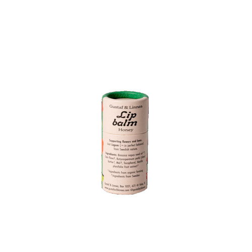 Lip balm tube, honey-colored, green top, white label, Gustaf & Linnea branding, ingredients listed.