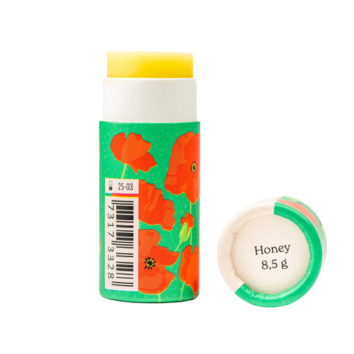 Lip balm tube with poppy design, green and white, yellow balm exposed, cap beside it.