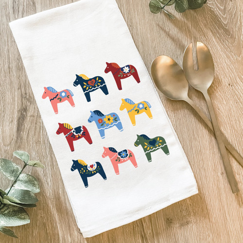 White flour sack towel with colorful Swedish Dala horses, gold salad servers