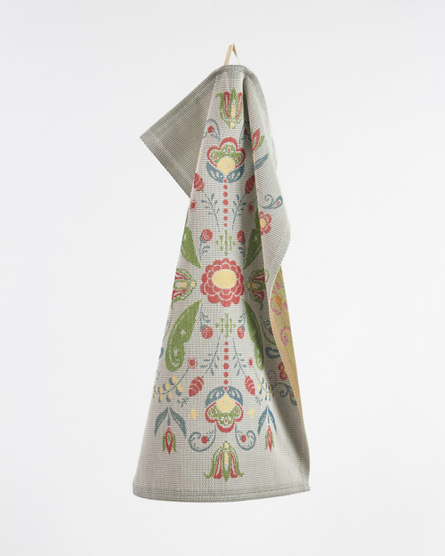 Folded gray cotton tea towel with Scandinavian green and red floral pattern hanging.