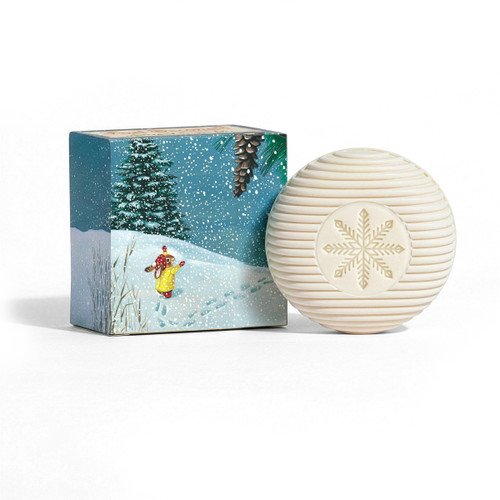 White round, ribbed soap with a snowflake medallion beside its illustrated holiday box.