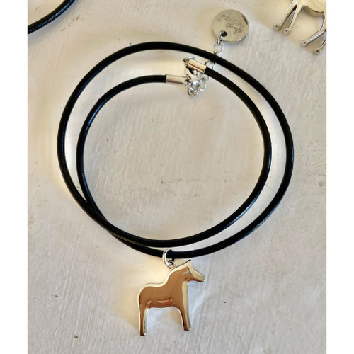 Anna Viktoria silver Dala horse pendant on a black leather double-strand necklace on a white surface.