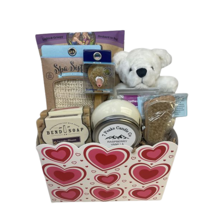 Valentine's Day Spa Sensations features Bend Soap Company Vienna Rose, Lavender Lemon goats milk soap, 7 Peaks Candle Co.  - Raspberry Vanilla scent, Sisters Fruit Company - Apple Chips, plush teddy bear, natural wooden foot brush, bamboo exfoliating face brush,  Siscal Soap Sak and Gather Nuts - Maple Cardamom Almonds.  Designed in an American made recyclable Valentine's container.