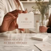 Business owner holding a cream square skincare business card above matching cards on a counter