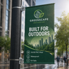 Green Greenscape Initiative outdoor pole banner mounted to a black street pole with metal brackets and bands.