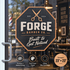 Black and orange octagon-shaped Forge Barber Co. window decal applied to a glass barbershop entrance.