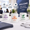 Three custom white mugs with colorful logos arranged for corporate event giveaways and promotional branding.