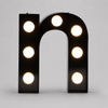 Warm glowing exposed bulb marquee channel letters illuminated on wall at night