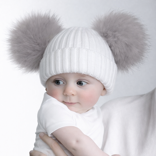 A soft ribbed knit baby hat in classic white, featuring a snug turnover cuff for added warmth and comfort. Finished with two fluffy GREY faux fur pom poms for a stylish and playful look. Suitable for newborns up to 12 months.
Composition: Hat – 100% acrylic, Pom poms – 100% polyester.
Pack: 1 piece with hook & hang tag label, 6 pieces per polybag.