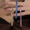 Trio of three bracelets hung from a hand- pave blue sapphire, diamond tennis and pink sapphire baguette bracelet