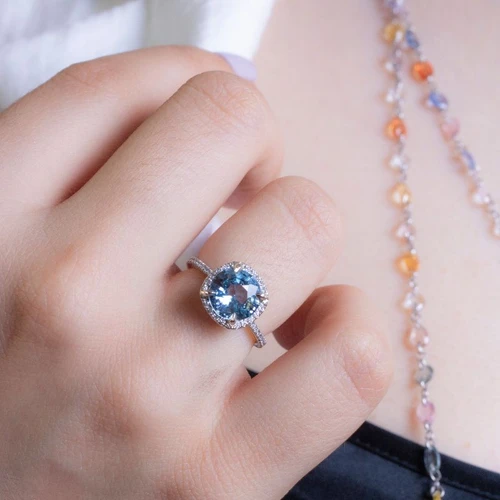 Round light blue sapphire halo cushion on hand