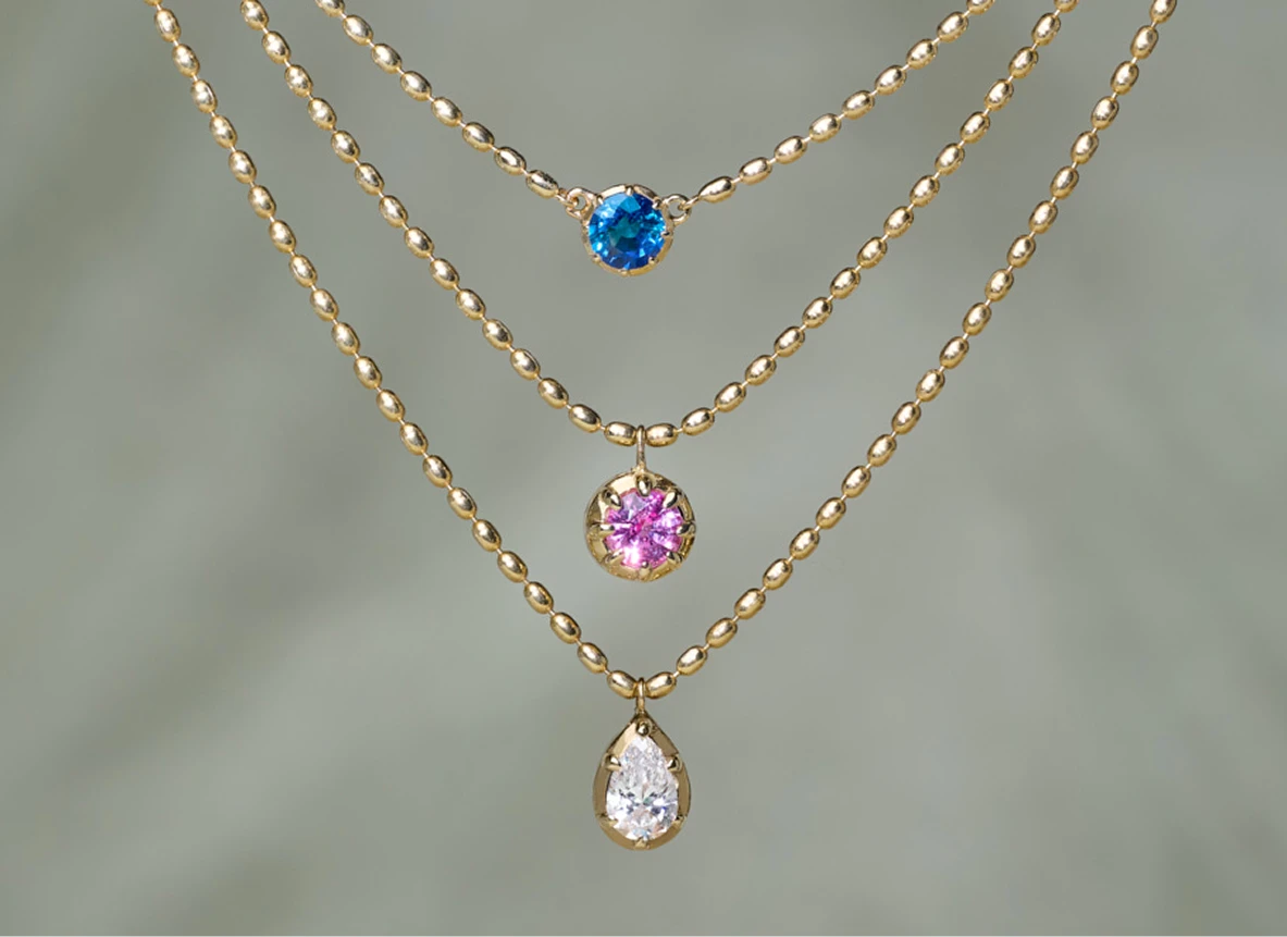 Gold bead chains with blue or pink sapphire and pear shaped diamond