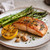Seared salmon with roasted asparagus, grilled lemon, garlic cloves, thyme, and rustic lemon garlic seasoning inspiration.