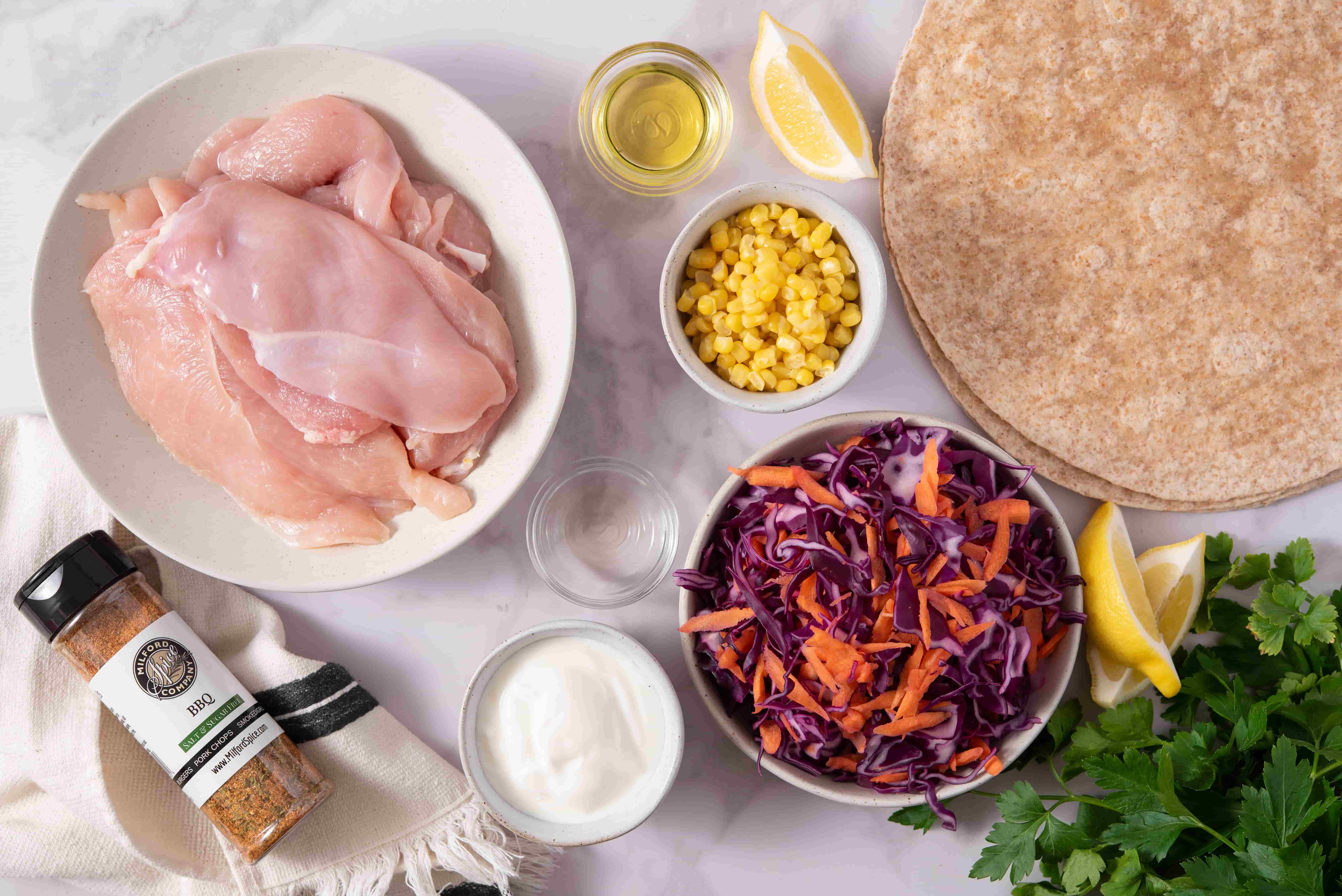 Ingredients for BBQ Chicken Tortilla Folds including chicken breasts, corn, red cabbage slaw, tortillas, lemon, yogurt, parsley, and Milford Spice Company BBQ Blend