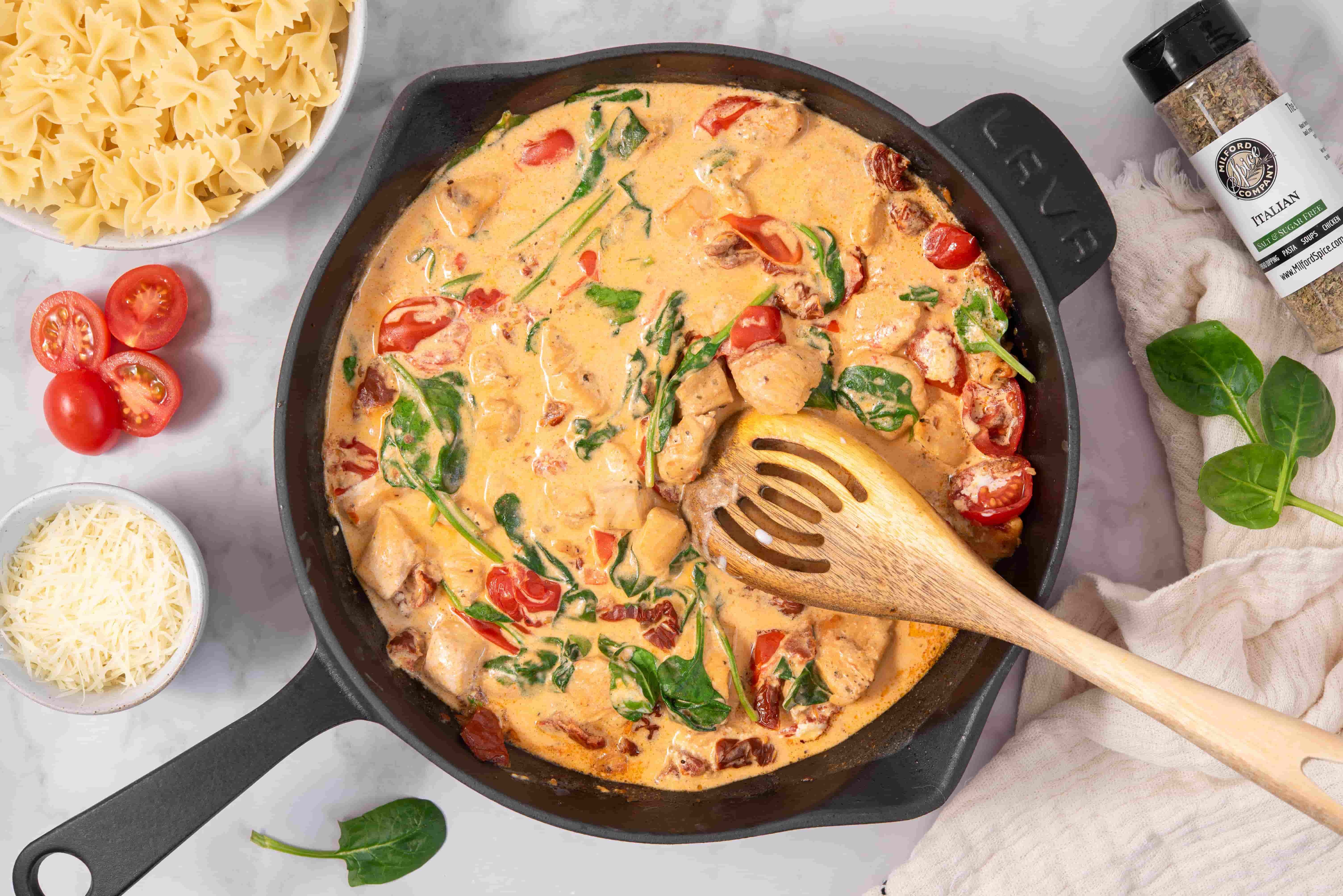 Creamy Marry Me Chicken sauce with spinach, cherry tomatoes, sun-dried tomatoes, and chicken in a skillet