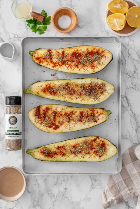 Eggplant halves seasoned with smoked paprika, Salt Free Italian herbs, olive oil, and salt on a baking sheet