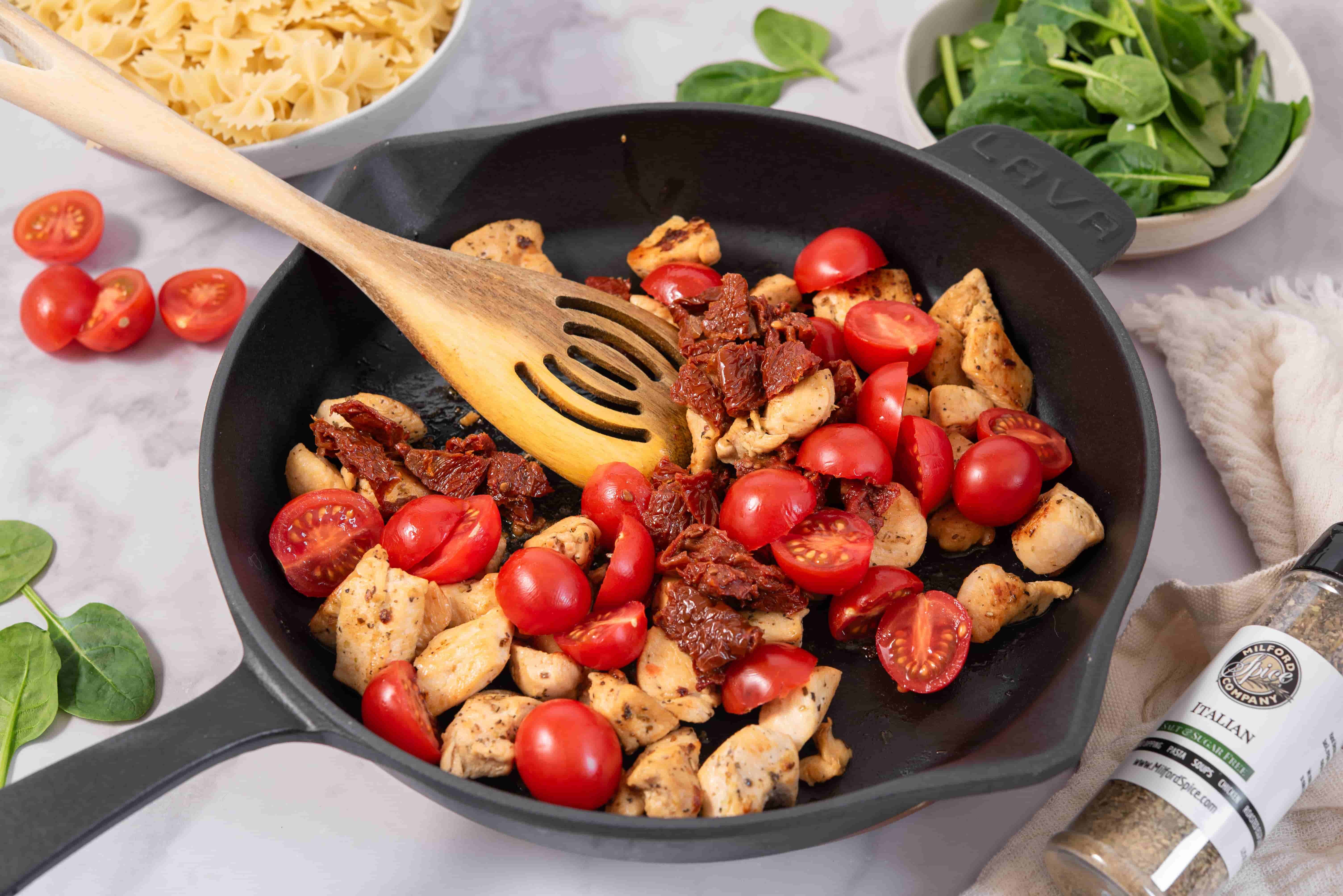 Chicken, cherry tomatoes, and sun-dried tomatoes cooking in a skillet for Marry Me Chicken Pasta