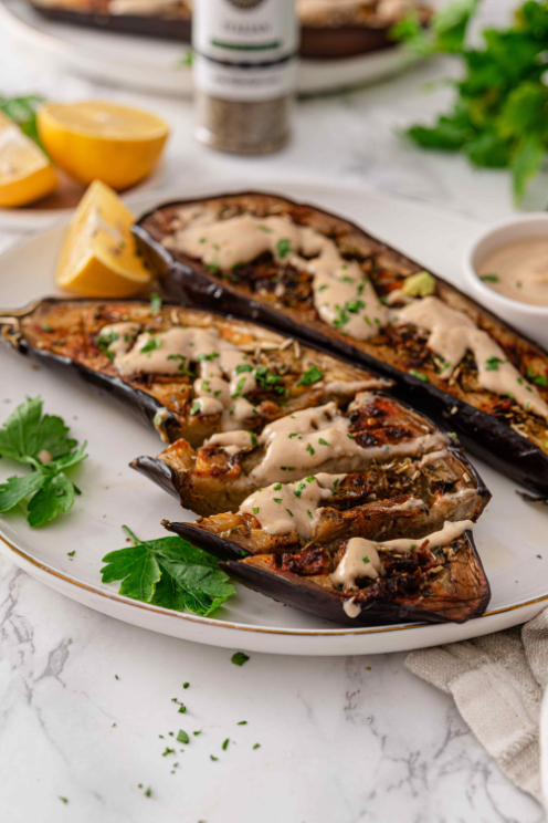 Roasted eggplant with lemon tahini sauce showing a tender bite and caramelized seasoned flesh