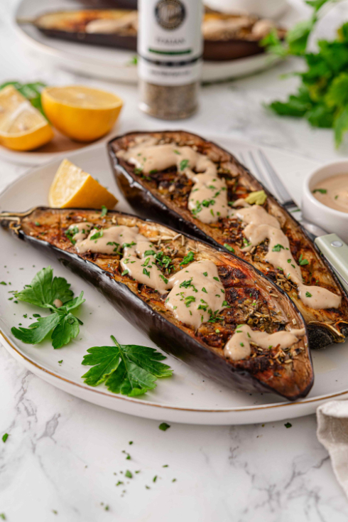 Close-up of roasted eggplant topped with creamy lemon tahini sauce and fresh parsley