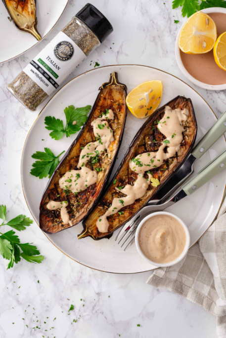 Roasted Italian Eggplant with Lemon Tahini Sauce served on a plate with Milford Spice Company Salt Free Italian, lemon wedges, parsley, and tahini sauce