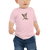 Baby in a pink, short sleeve tee featuring an original illustration of a sheep / goat / kangaroo?