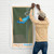 Man hanging a wall flag illustrated with a cute, orange kitty sitting on a swim springboard