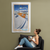 A sitting woman drinks coffee while admiring a wall banner illustrated with a cute, white Labrador puppy on a ski chair lift