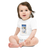 Baby in a white, short sleeve baby onesie featuring an illustration of a chocolate brown labrador puppy sitting in a ski chair lift